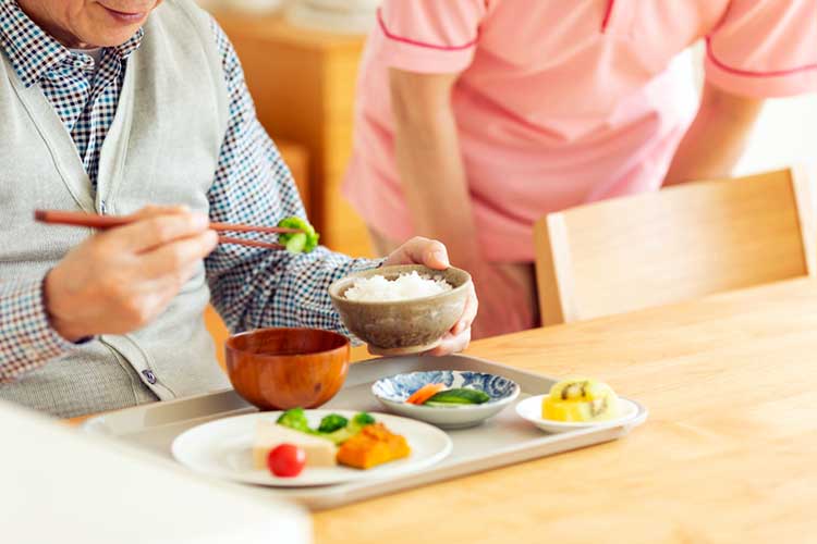 man eats meal with chopsticks in aged care facility