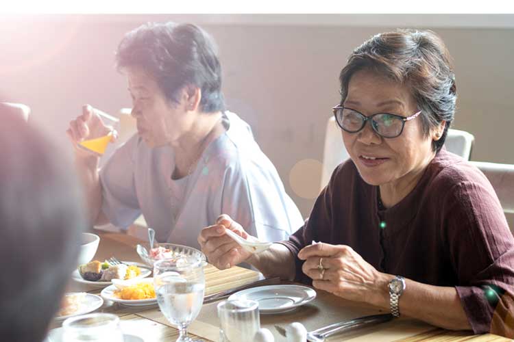 woman eats with friends in aged care facility