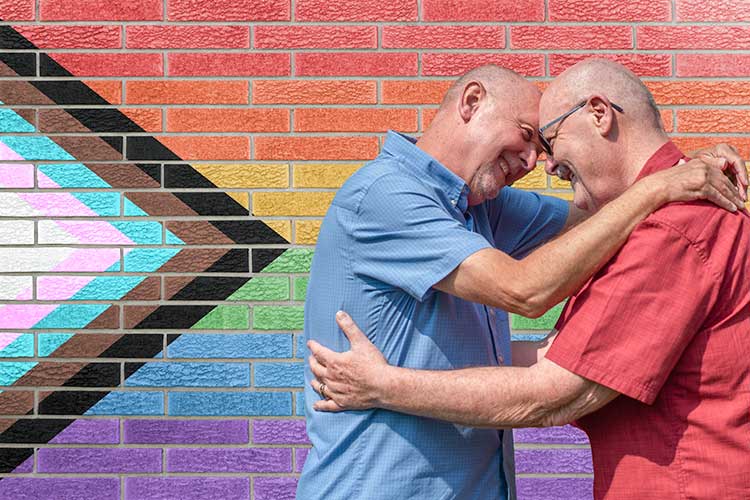 older LGBTIQ+ couple in front of pride flag