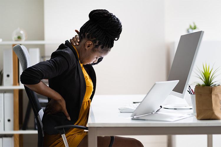 woman sitting at deak holding her back and neck in discomfort
