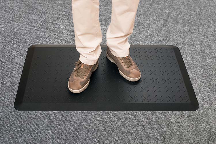 close-up of person's shoes standing on black floor mat