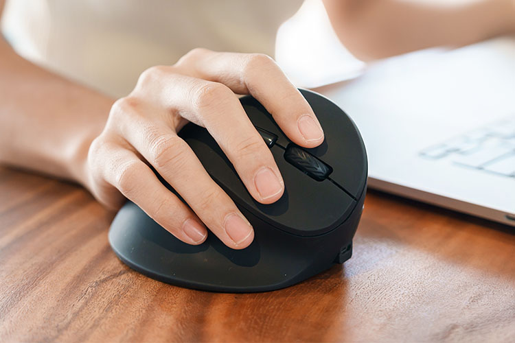 close-up of woman using ergonomic mouse to work on a laptop