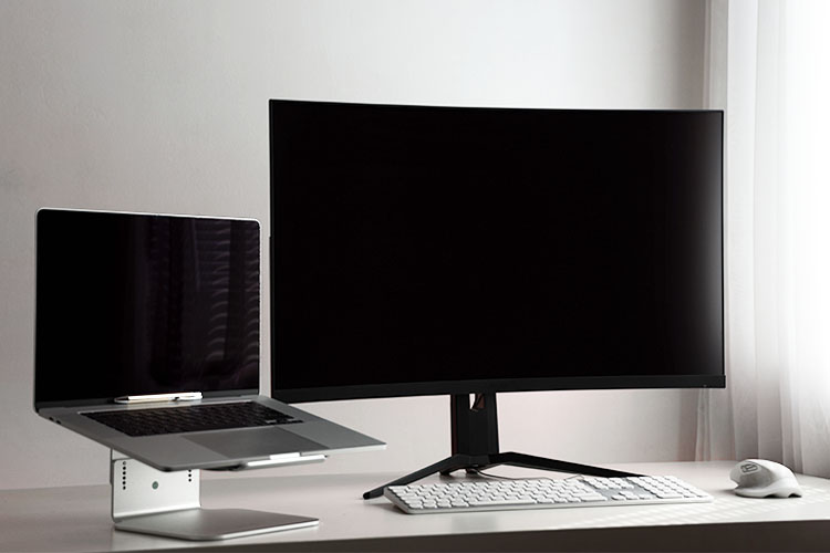 dual screen set-up with laptop on raised stand on left and monitor on right
